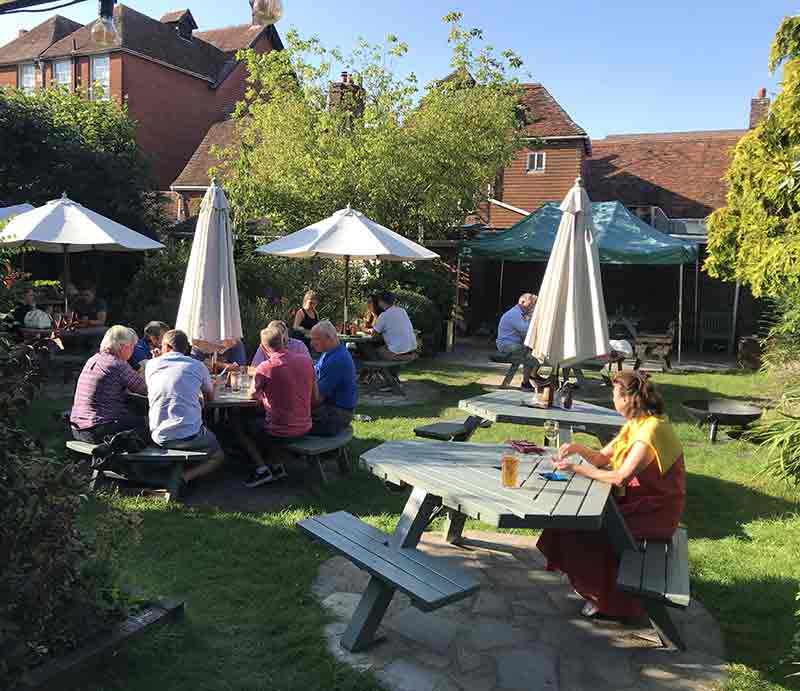 Customers enjoying a drink in the pub garden on a sunny day.